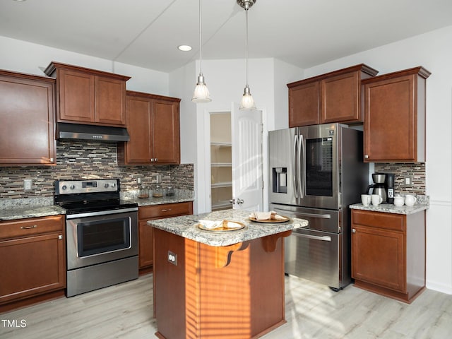 kitchen featuring hanging light fixtures, light stone countertops, appliances with stainless steel finishes, a kitchen island, and a kitchen bar