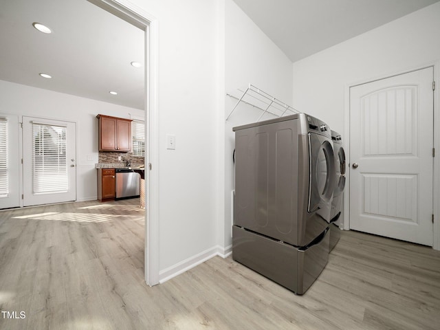 washroom with washing machine and dryer and light hardwood / wood-style flooring