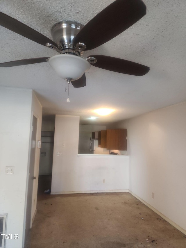 unfurnished living room with ceiling fan and a textured ceiling