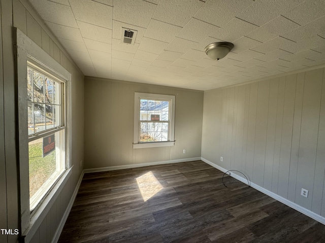 empty room featuring dark hardwood / wood-style flooring and wooden walls