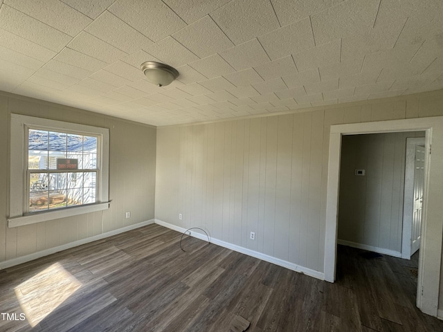 unfurnished room with dark hardwood / wood-style floors and wood walls