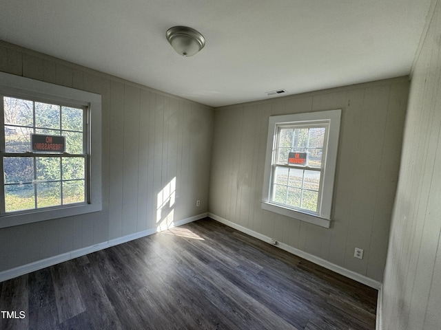 unfurnished room featuring dark hardwood / wood-style flooring and wooden walls