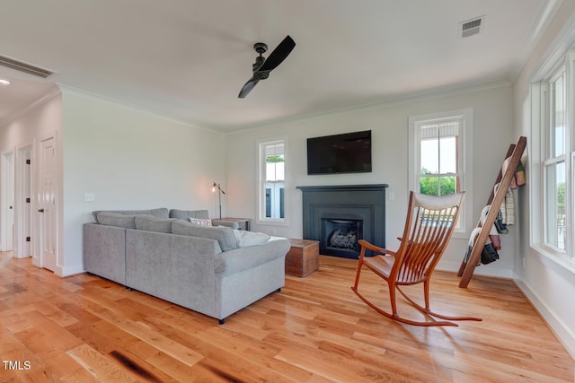 living room with ceiling fan, light wood-type flooring, and ornamental molding