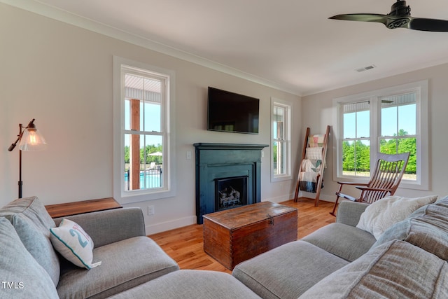 living room with ceiling fan, light wood-type flooring, and ornamental molding