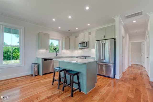 kitchen featuring stainless steel appliances, tasteful backsplash, light hardwood / wood-style floors, a breakfast bar, and a kitchen island