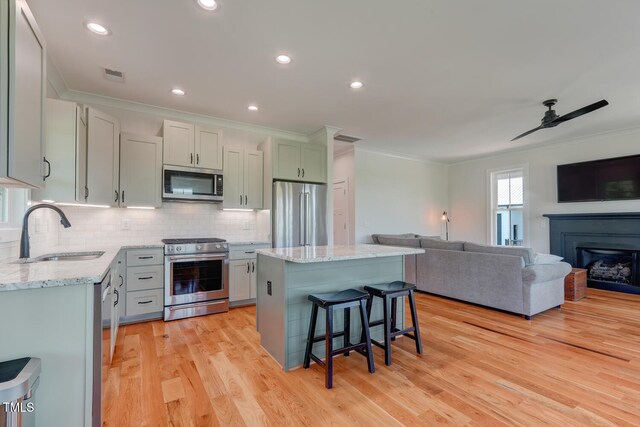 kitchen with a center island, backsplash, sink, light hardwood / wood-style floors, and stainless steel appliances