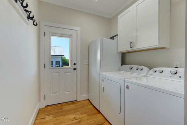 laundry area featuring washer and dryer, light hardwood / wood-style floors, and cabinets