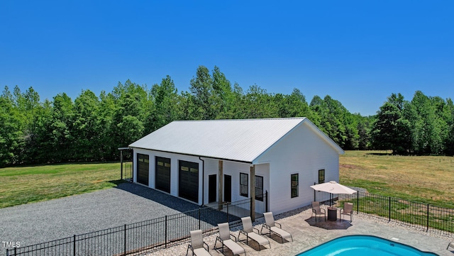 back of property featuring a yard, an outdoor structure, a garage, a fenced in pool, and a patio