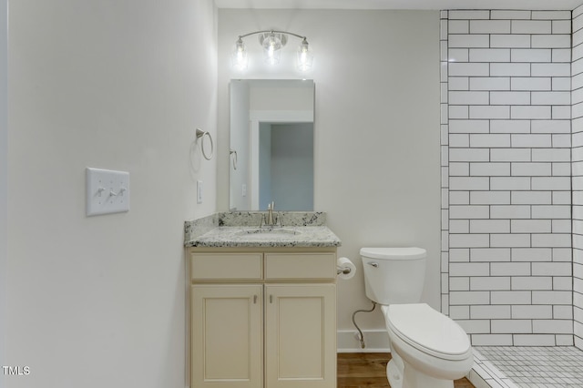 bathroom with a tile shower, vanity, and toilet