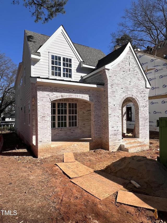 view of front of property with brick siding and a shingled roof