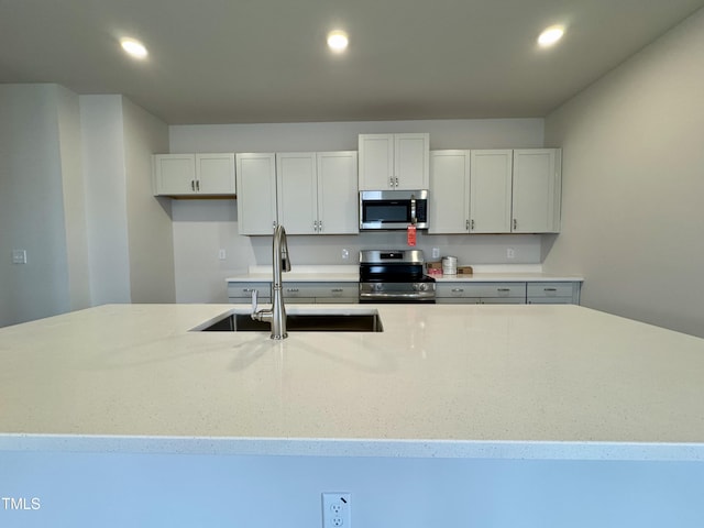 kitchen with white cabinets, sink, light stone countertops, and stainless steel appliances