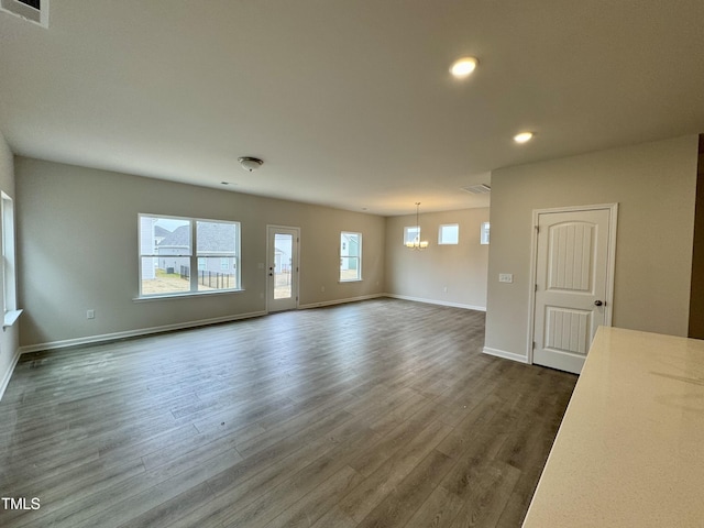 unfurnished living room featuring dark wood-type flooring and an inviting chandelier