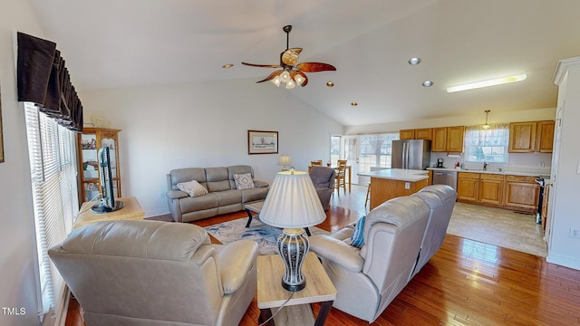 living room featuring light hardwood / wood-style flooring, vaulted ceiling, ceiling fan, and sink