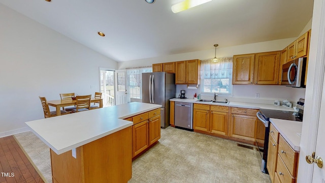 kitchen featuring light hardwood / wood-style flooring, vaulted ceiling, decorative light fixtures, a kitchen island, and appliances with stainless steel finishes