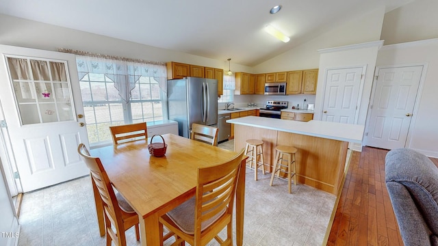 dining room featuring sink, light hardwood / wood-style flooring, and vaulted ceiling