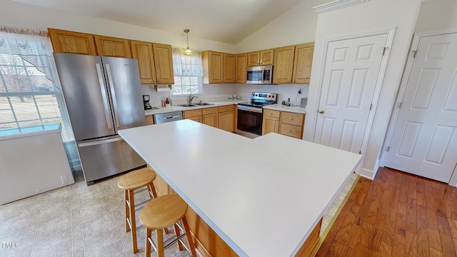 kitchen with a kitchen island, light hardwood / wood-style floors, stainless steel appliances, and hanging light fixtures