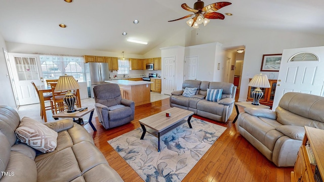 living room featuring ceiling fan, light hardwood / wood-style flooring, high vaulted ceiling, and sink