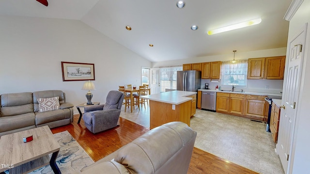 kitchen featuring lofted ceiling, sink, appliances with stainless steel finishes, decorative light fixtures, and a kitchen island