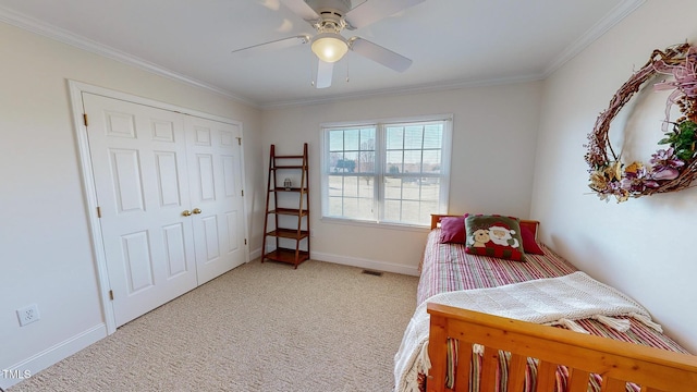 bedroom with ceiling fan, a closet, light carpet, and ornamental molding