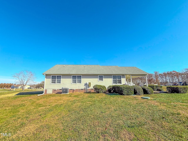 back of property with a yard and central AC