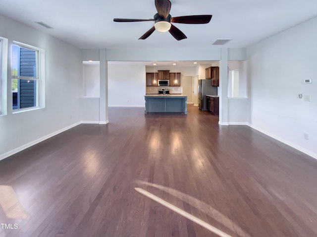 unfurnished living room featuring ceiling fan and dark wood-type flooring