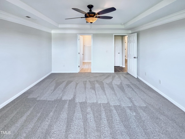 spare room featuring a tray ceiling, ceiling fan, carpet floors, and ornamental molding