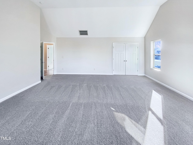 empty room with dark colored carpet and lofted ceiling