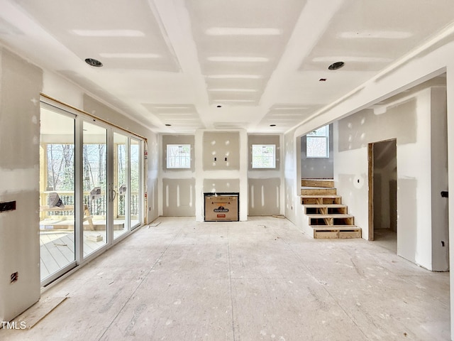 unfurnished living room featuring a healthy amount of sunlight and stairway