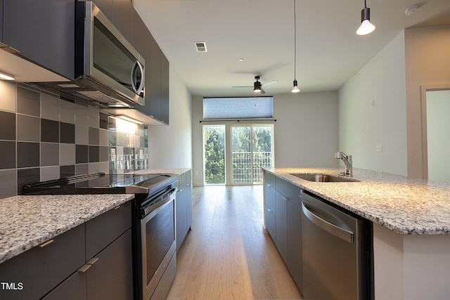 kitchen featuring ceiling fan, sink, hanging light fixtures, an island with sink, and appliances with stainless steel finishes