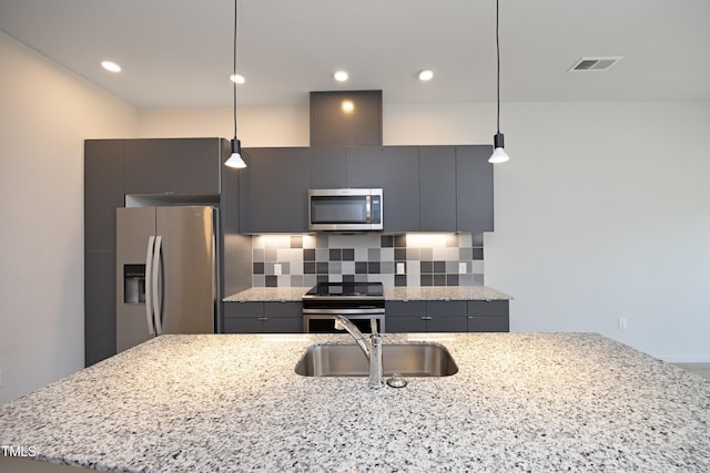 kitchen with backsplash, stainless steel appliances, light stone counters, and hanging light fixtures