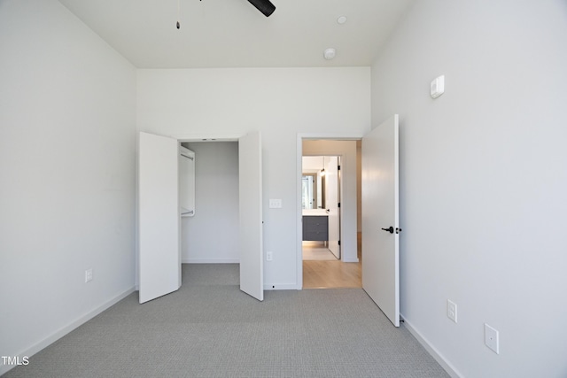 unfurnished bedroom featuring light carpet, a closet, and ceiling fan