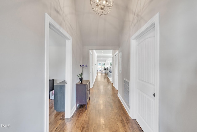 corridor featuring hardwood / wood-style floors and an inviting chandelier