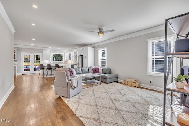 living room featuring french doors, light hardwood / wood-style flooring, ceiling fan, and ornamental molding