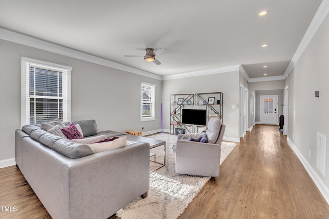 living room featuring crown molding, light hardwood / wood-style flooring, and ceiling fan