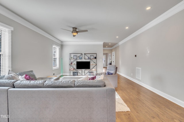 living room with crown molding, plenty of natural light, ceiling fan, and light hardwood / wood-style flooring