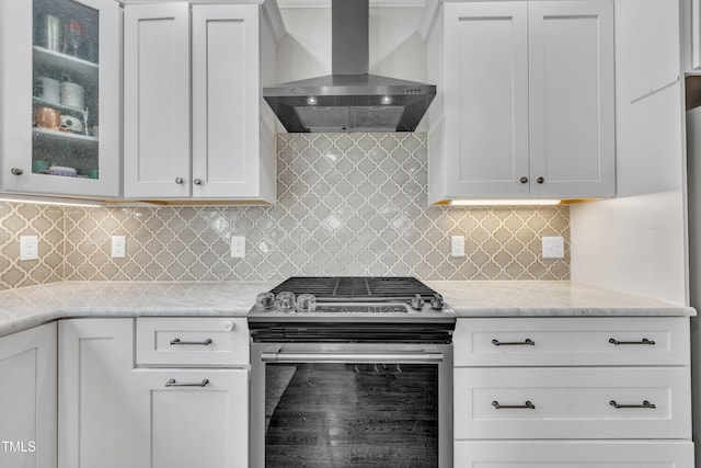 kitchen with backsplash, white cabinets, wall chimney range hood, stainless steel stove, and light stone counters