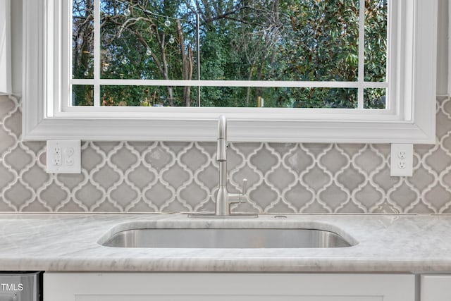 kitchen featuring plenty of natural light, white cabinetry, light stone countertops, and sink