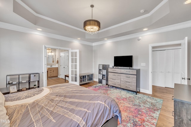 bedroom with light hardwood / wood-style floors, a raised ceiling, and ornamental molding