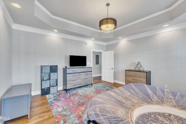 bedroom featuring a chandelier, a raised ceiling, light hardwood / wood-style flooring, and ornamental molding