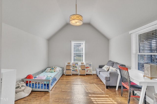 bedroom with vaulted ceiling, a crib, and hardwood / wood-style flooring