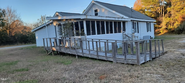 rear view of property featuring a sunroom and a wooden deck