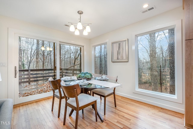 dining space with light hardwood / wood-style floors, an inviting chandelier, and a wealth of natural light