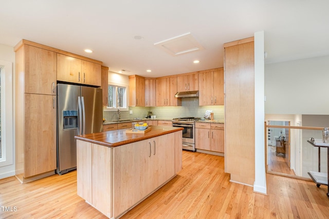 kitchen featuring decorative backsplash, light brown cabinetry, light wood-type flooring, stainless steel appliances, and a center island