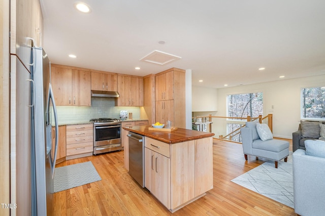 kitchen with appliances with stainless steel finishes, backsplash, light brown cabinets, light hardwood / wood-style floors, and butcher block counters