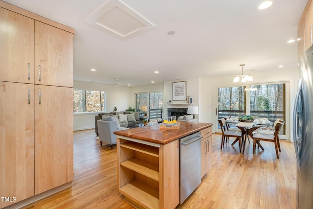 kitchen featuring light brown cabinets, light wood-type flooring, stainless steel appliances, and pendant lighting