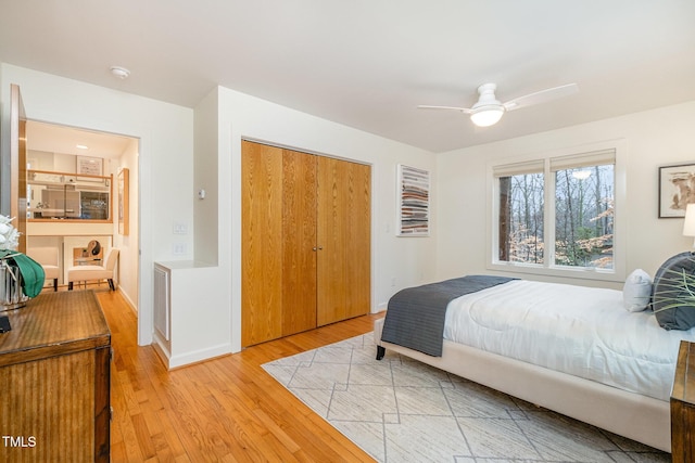 bedroom featuring ceiling fan, light hardwood / wood-style flooring, and a closet