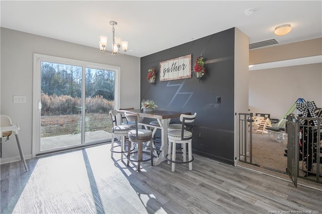 dining space with hardwood / wood-style floors and a notable chandelier