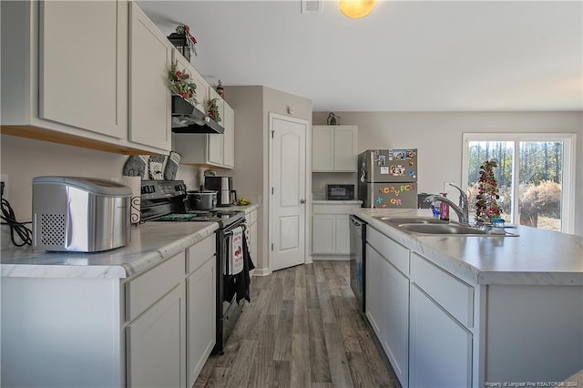 kitchen featuring appliances with stainless steel finishes, sink, a center island with sink, white cabinets, and hardwood / wood-style floors