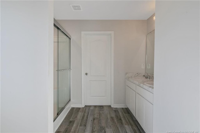 bathroom featuring hardwood / wood-style floors, vanity, and a shower with door