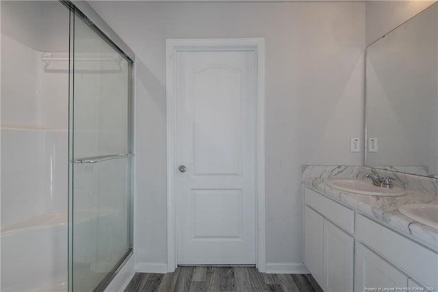 bathroom with hardwood / wood-style floors, vanity, and a shower with door